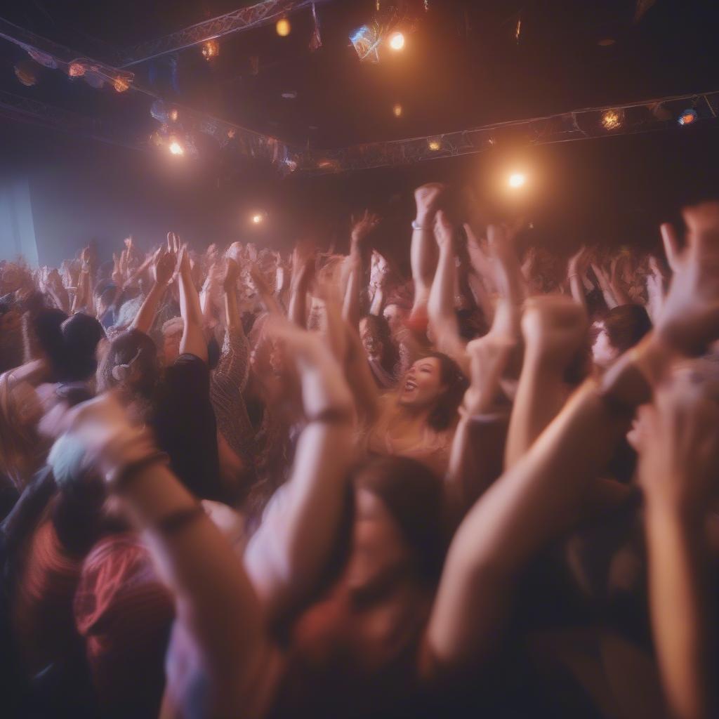 A large crowd of people enjoying a party atmosphere, with hands raised and smiles on their faces.